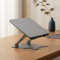 Ergora Vantage foldable laptop stand in space grey on a warm oak desk